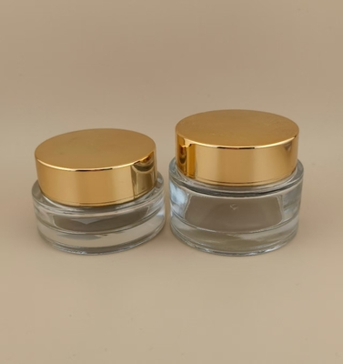 Vaso di crema di vetro trasparente con coperchio a vite dorata per lozione femminile